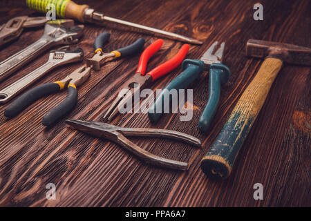 Différents outils de travail sur une table en bois - un marteau, pinces coupantes, pinces, ciseaux et clés Banque D'Images