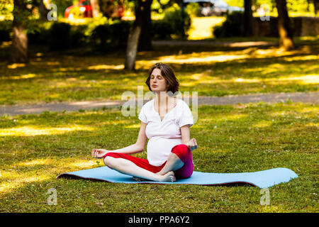 Femme enceinte à l'extérieur dans la nature faisant du yoga Banque D'Images