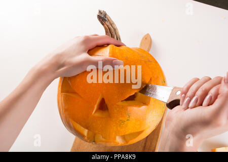 Fille main faire jack o lanterne pour Halloween vacances avec couteau de cuisine. L'oeil sur les grandes réductions orange citrouille. Close up, selective focus Banque D'Images