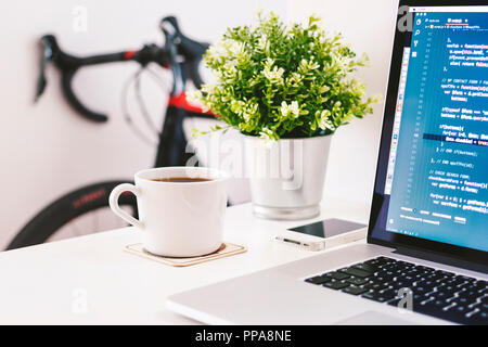 Bureau d'accueil avec café et portable sur tableau blanc avec vélo de route à l'arrière-plan Banque D'Images