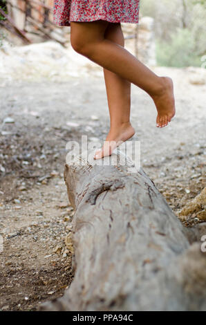 Robe fille fleurs hippies avec marche pieds nus sur un grand stump Banque D'Images