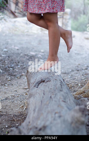 Robe fille fleurs hippies avec marche pieds nus sur un grand stump Banque D'Images