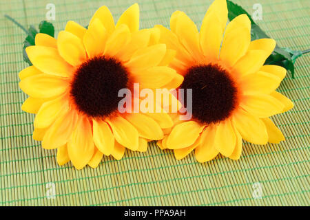 Fleurs en tissu jaune sur fond de bambou, gros plan photo. Banque D'Images