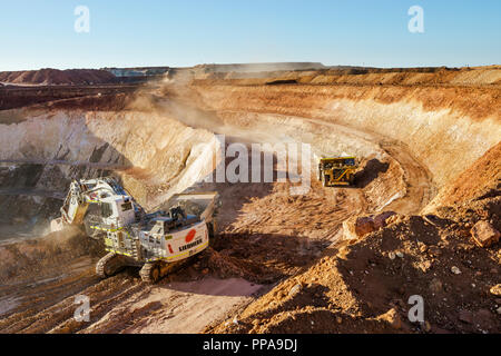 Les camions d'être chargé de minerai par digger en mine à ciel ouvert, l'ouest de l'Australie Banque D'Images