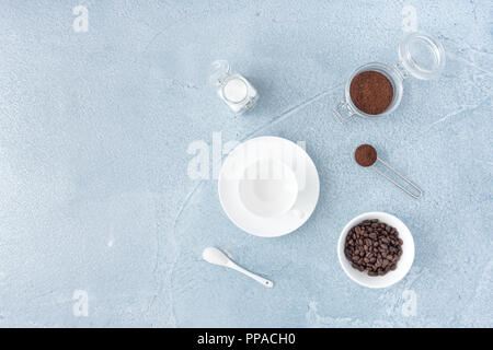 Les grains de café, café moulu et le sucre blanc et une tasse de café vide sur fond de béton bleu. Banque D'Images