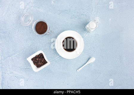 Nature morte avec du café noir dans la tasse, café en grains, du café moulu et le sucre blanc bleu sur fond de béton. Banque D'Images