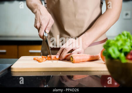 Vue rapprochée de l'homme de trancher la main sur la carotte à découper dans la cuisine Banque D'Images