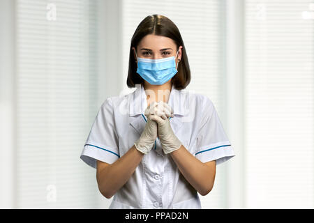 Jolie femme médecin au masque médical. Jeune femme médecin portant masque et des gants en caoutchouc. Prêt à fonctionner. Banque D'Images