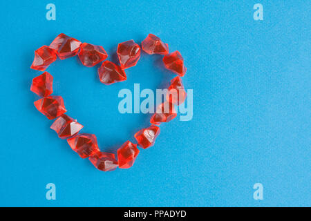 Coeur de pierres en plastique orange sur fond bleu Banque D'Images