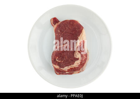 Un morceau de viande crue (ripe) steak sur une plaque blanche sur un fond isolé Banque D'Images