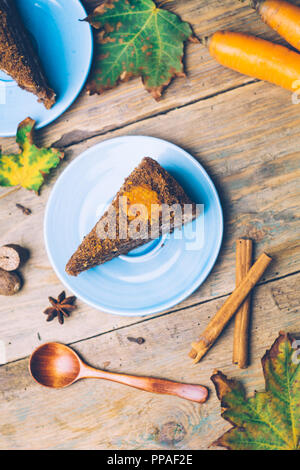 Gâteau de carotte (desserts maison) avec des bâtons de cannelle et décoré avec des épices sur fond de bois Banque D'Images