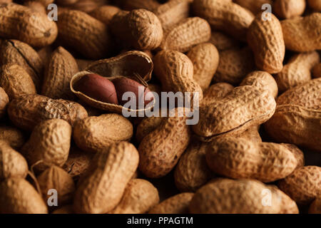 Arachides non pelées en remplissant le cadre ; une arachide ouvert est la vedette de la composition. Focus sélectif. Banque D'Images