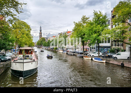 Il s'agit d'une photo d'un des nombreux canaux d'Amsterdam. Il y a un grand bateau dans le premier plan et une église dans l'arrière-plan Banque D'Images