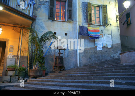 RIOMAGGIORE ITALIE -Le 26 avril 2011 ; Grande étapes conduisant de rustique bâtiments typiques avec des lumières à travers les fenêtres et les serviettes laissé pour compte. Banque D'Images