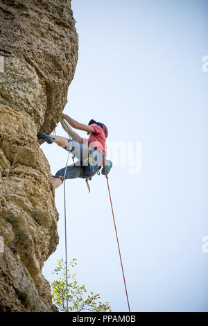 Photo de femme athlète casque en accrochant sur rock Banque D'Images