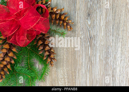 Un arc rouge et trois pommes de pin blanc sur des branches d'épinette with copy space Banque D'Images