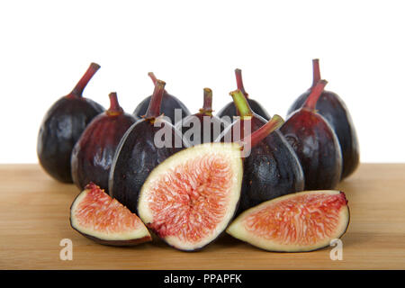 Figues fraîches entières sur une table en bois avec des tranches de figues face viewer, isolé sur fond blanc. Banque D'Images