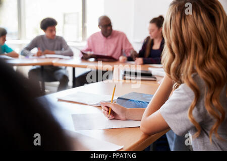 Female High School Student Writing Notes assis au bureau de la classe Banque D'Images