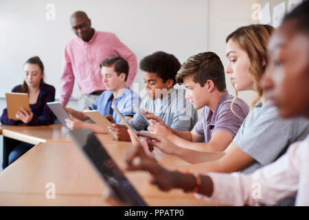 Professeur de lycée avec des élèves à l'aide de tablettes numériques en classe de technologie Banque D'Images