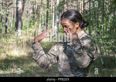 Le Sgt. Shuntaneque Greenwald, U.S. Army NATO Brigade, fans son visage pour verser le monosulfure de carbone (gaz CS) au cours de la 2018 Meilleur guerrier européen concours tenu lors de la 7e formation de l'Armée de la commande Zone d'entraînement Grafenwoehr, Allemagne, le 13 août 2018. Les gagnants du concours seront annoncés pour cette année, le haut fonctionnaire subalterne, sous-officier et soldat au cours d'une cérémonie de clôture prévue pour le 17 août 2018. Banque D'Images