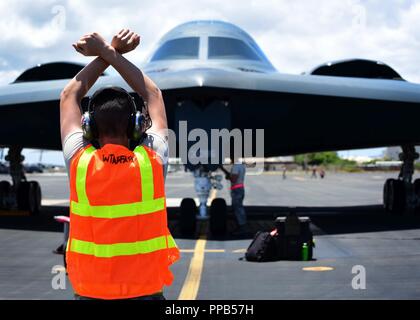 Un technicien de maintenance de l'US Air Force, déployés à partir de Whiteman Air Force Base, Alabama, marshals un B-2 Spirit au Joint Base Harbor-Hickam Pearl, Washington, 15 août 2018. B-2s font régulièrement des stages dans l'Indo-Pacifique pour mener des opérations aériennes, qui intègrent des capacités avec les principaux partenaires régionaux et de démontrer l'engagement des États-Unis pour la paix et la stabilité dans la région. Ces opérations sont à l'appui du Commandement stratégique américain Bomber's Task Force de déploiement. Banque D'Images