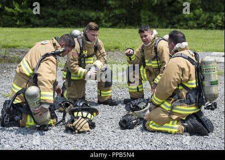 Réserve de l'US Air Force les pompiers citoyens discutent de la manière dont ils ont travaillé ensemble en équipe après une simulation d'extinction d'incendie de voiture au cours d'un exercice guerrier patriote à Dobbins Air Reserve Base, la Géorgie, le 13 août 2018. Préparer des exercices de guerrier patriote citoyen réserve expéditionnaire aviateurs pour les déploiements à l'échelle mondiale et fournit des connaissances et l'expérience pour renforcer les programmes de formation à la maison mère. De gauche à droite : Senior Airman Warren Duc avec le 624th Escadron de génie civil, d'une base commune Pearl Harbor-Hickam, Texas, Senior Airman Matthieu Southwick avec le 746e Escadron de génie civil de l'unité conjointe Banque D'Images