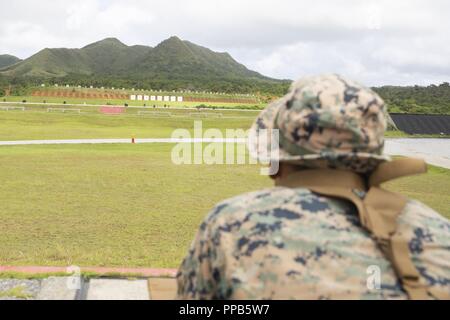 Le Cpl. Justin Lara attend que son fusil d'être effacés à la fin de l'allumage sur le champ de tir de l'adresse au tir de combat au cours d'un cours d'entraîneurs au Camp Hansen, Okinawa, Japon, 14 août 2018. Lara, originaire d'Austin, Texas, et d'un fantassin du 2e Bataillon, 3e Régiment de Marines. "J'ai tourné quatre fois d'experts, cette fois va être la cinquième," dit-il. Lara a dit qu'il a hâte d'être sur le fusil et se déplacer pour le prochain défi dans le cours. Le cours couvre également la prise de distance inconnue, nuit, et champ de tir. Banque D'Images