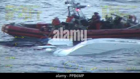 Un garde-côte de William Flores petit bateau équipage tire deux personnes de l'eau après un 25 pieds de Grady de plaisance blanc prend l'eau Vendredi, 16 août 2018 à environ 34 milles à l'est de Lake Worth, en Floride. La faucheuse William Flores équipage reçoit un appel de détresse du navire ont indiqué qu'ils étaient pris sur l'eau et l'équipage coupe détournées pour aider les plaisanciers. Banque D'Images