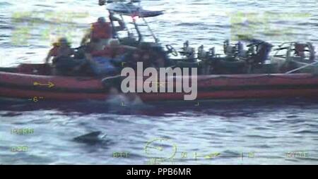 Un garde-côte de William Flores petit bateau équipage tire deux personnes de l'eau après un 25 pieds de Grady de plaisance blanc prend l'eau Vendredi, 16 août 2018 à environ 34 milles à l'est de Lake Worth, en Floride. La faucheuse William Flores équipage reçoit un appel de détresse du navire ont indiqué qu'ils étaient pris sur l'eau et l'équipage coupe détournées pour aider les plaisanciers. Banque D'Images