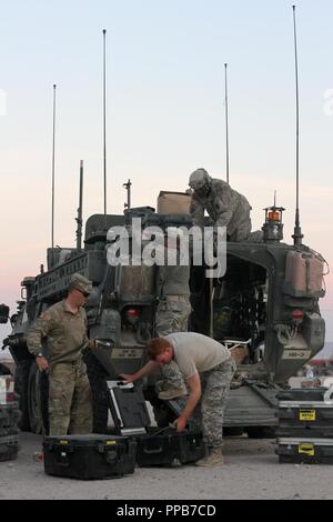 Le Sgt. James Quinn, un fantassin, SPC. Matthieu Schluckebier, un pilote de Stryker, Sgt. Rudolph Vorndran, un pétrolier, et le sergent. Deron Dixon, un commandant Stryker véhicule, tous attachés à l'Administration centrale et de l'Administration centrale, de l'entreprise 56e Stryker Brigade Combat Team, 28e Division d'infanterie, New Jersey Army National Guard, travailler sur le retrait montés sur véhicule, système intégré de prises à parties multiples au laser (MILES) à partir d'un pignon de Stryker en arrivant dans le cantonnement après une formation rigoureuse dans la bataille simulé au Centre National d'entraînement, Fort Irwin, en Californie, le 17 août. L'engrenage MILES permet aux soldats t Banque D'Images