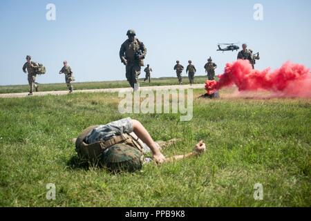 La Marine américaine corpsmen avec force de rotation de la mer Noire 18,1 et de la Royal Air Force avec le personnel médical de l'Escadre aérienne de la Force expéditionnaire britannique 135e déplacer pour aider les blessés et théoriquement-marines des civils après l'arrivée de l'armée américaine via UH-60 Black Hawk lors d'une évacuation sanitaire (EVASAN) percer à la base aérienne de Mihail Kogalniceanu, Roumanie, 16 août 2018. La simulation de l'évacuation sanitaire de formation théoriquement-blessés et de civils, la validation des Marines, combiné aux programmes conjoints/intégrés procédures médicales en cas d'événement grave. Banque D'Images