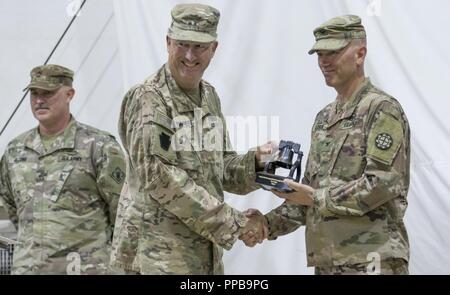 L'Armée américaine, le Général Andrew Schafer, général commandant de la 28e Division d'infanterie, remet un cadeau à l'ARMÉE AMÉRICAINE Le Colonel Anthony Adrian, commandant de la 35e Brigade du génie, pour montrer sa reconnaissance pour tout le travail effectué par le 35e EB au cours de leur déploiement, au cours d'une cérémonie de transfert d'autorité s'est déroulée au Camp Buehring, Koweït, 16 août 2018. La cérémonie de transfert d'autorité est tenue pour symboliser la conclusion d'une mission de l'unité et le début d'une autre. Banque D'Images