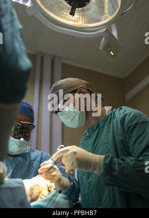 Le Sgt. Anthony Triolo, spécialiste d'une salle d'opération attribuée à l'Hôpital de Soutien au Combat 28, aide une équipe de personnel médical rwandais avec une opération chirurgicale au cours de MEDRETE 18-5, 20 août 2018, à l'hôpital militaire du Rwanda, Kigali, Rwanda. Cette année marque la première année MEDRETE avec la communauté médicale. MEDRETE est un effort combiné entre le gouvernement rwandais et l'Afrique de l'armée américaine. MEDRETE 18-5 fait partie d'une série d'exercices de formation à la préparation médicale de l'armée américaine que l'Afrique a facilité dans divers pays d'Afrique, et sert d'occasion pour la p Banque D'Images