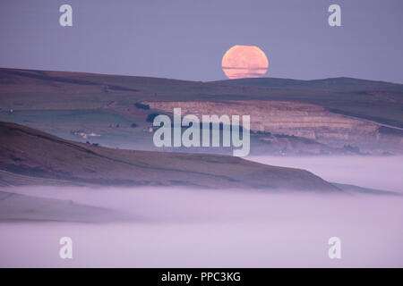 Vallée de l'espoir, Derbyshire, Royaume-Uni. 25 septembre 2018. La pleine lune se couche sur une vallée remplie de brouillard d'espoir dans le parc national de Peak District dans les premières heures du 25 septembre 2018. Connu sous le nom de Harvest Moon, la pleine lune la plus proche de l'Équinoxe, il prend une teinte orange du soleil se levant à l'autre côté du ciel. Credit : Graham Dunn/Alamy Live News Banque D'Images