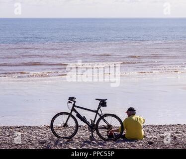 La ville de Sidmouth, Devon, le 25 sept 18 Un homme prend son vélo sur la plage de Sidmouth sur un jour de soleil. Dans Ttemperatures la faible entre 20 devrait se poursuivre tout au long de la semaine dans le Devon. Central Photo/Alamy Live News Banque D'Images