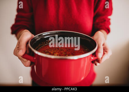 Les mains tenant pot rouge avec soupe aux légumes. Concept d'aliments sains Banque D'Images