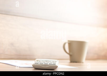 Calculatrice du périphérique et du document se trouvant sur la table en bois avec une tasse de café sur le côté. Banque D'Images