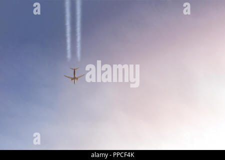 Vol d'un avion de passagers en haut ciel clair blanc quitter les sentiers. Gros avion voler pendant l'heure du coucher du soleil avec ciel dramatique sur l'arrière-plan. Concept de voyage et d'aviation. Copyspace Banque D'Images