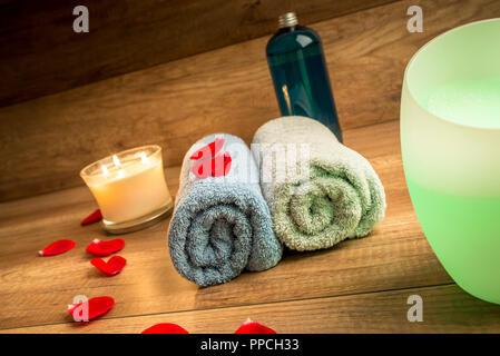 Romantic Spa Still Life Concept for a Couple with Two Rolled Towels, Lit Candle, Bottle of Massage Oil and Essential Oil Diffuser Surrounded by Red Ro Banque D'Images
