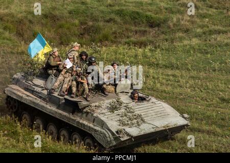 Les soldats ukrainiens monter en haut d'un BMP avec pavillon ukrainien pendant un exercice au Rapid Trident 18 tenue à la CCT de Yavoriv, l'Ukraine, le 3 septembre. Banque D'Images