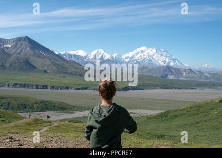 Femelle adulte se trouve en face de montagnes Denali dans la chaîne de l'Alaska de Denali National Park. Concept pour femme voyageant seule, la confiance de voyage Banque D'Images