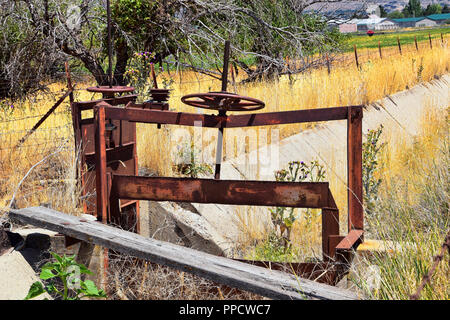 Paire de treuil de rusty irrigation antiques gates contre ciel avec de hautes herbes en Heber City, Utah le long de la face arrière de la Wasatch Front Rocky M Banque D'Images