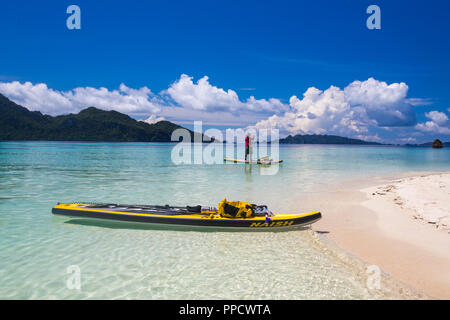 Vue éloignée de man paddleboarding en mer près de plage, Misool, Raja Ampat, Indonésie Banque D'Images