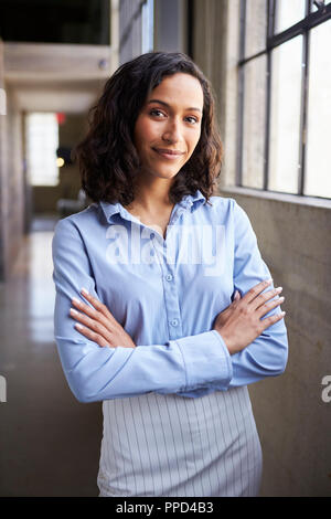 Young mixed race businesswoman standing with arms crossed Banque D'Images