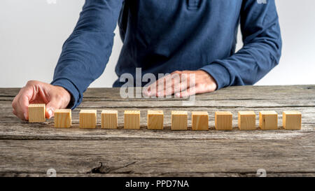 Vue avant de placer un homme blanc de 12 cubes en bois dans une rangée sur une texture 24. Banque D'Images