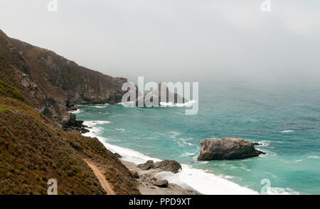 Un littoral rocheux calfornia avec brouillard enveloppant les collines au loin. Banque D'Images