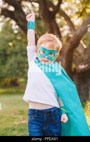 Cute adorable preschool caucasien enfant jouant en costume de super-héros. Kid garçon portant masque et le cap vert s'amuser en plein air dans le parc. Happy active ch Banque D'Images