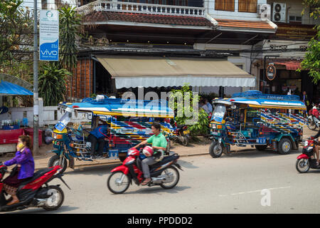 Les scooters et deux-roues en stationnement trois taxis colorés appelé jumbo (ou tuk-tuk) sur la route Sisavangvong à Luang Prabang, Laos, lors d'une journée ensoleillée. Banque D'Images