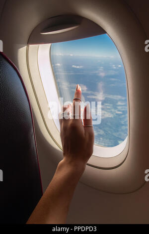 Femme à la fenêtre à travers de l'avion pendant le lever du soleil. Banque D'Images