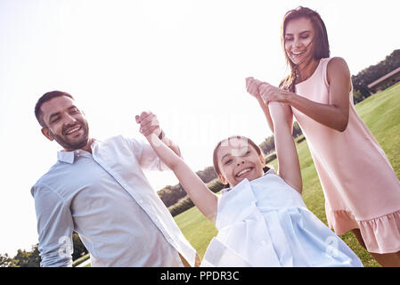 Le collage, la famille de trois walking on grassy field in daughte Banque D'Images